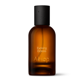 Amber glass Aesop Evoking Eidesis Eau de Parfum bottle with black cap on a white background.
