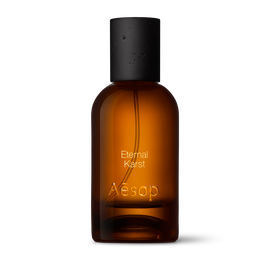 Amber glass Aesop Eternal Karst Eau de Parfum bottle with black cap on a white background.
