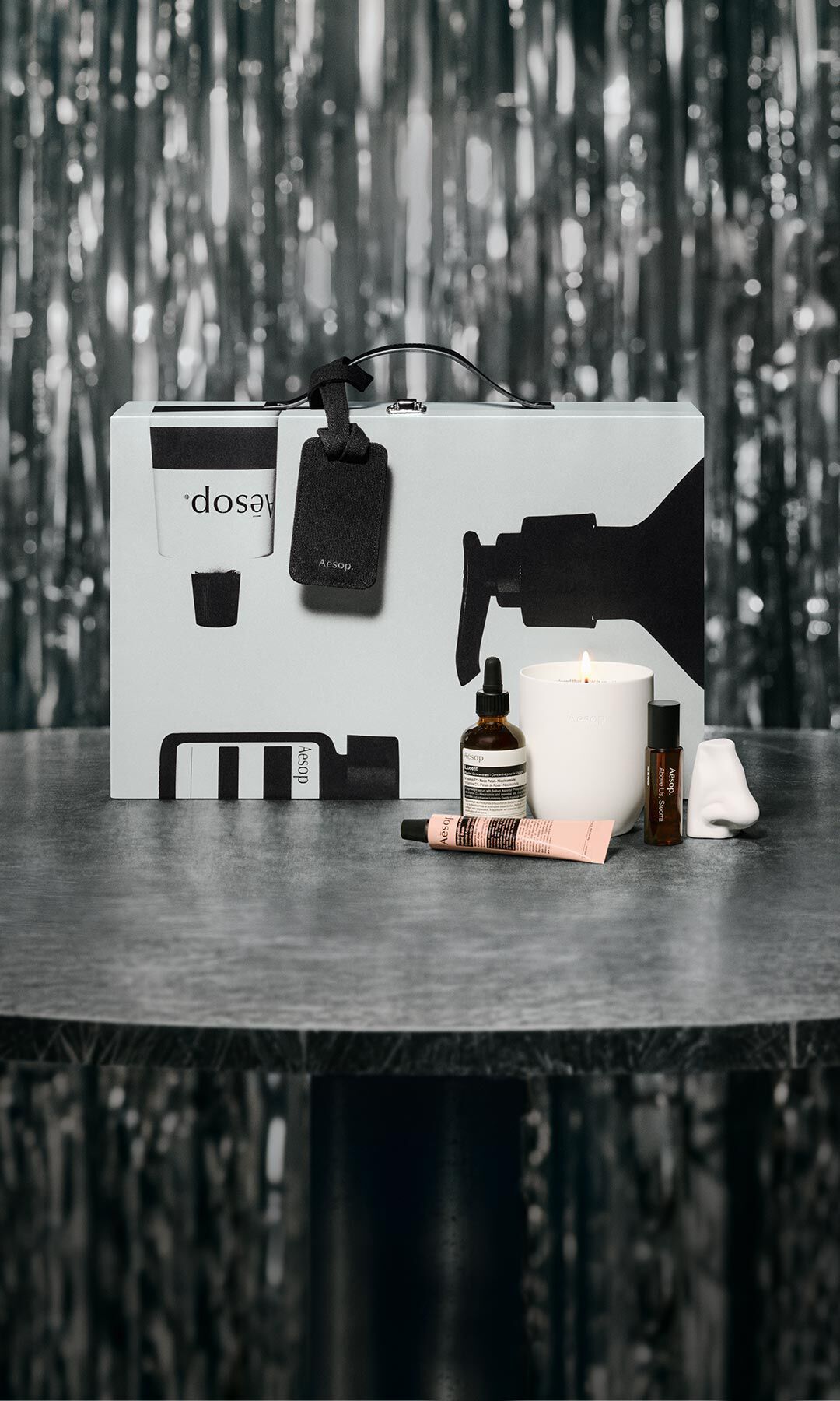 Aesop gift set and skincare products arranged on a table against a festive, softly lit backdrop.