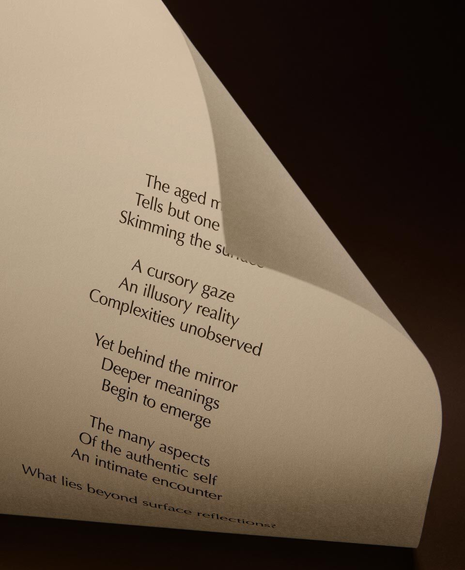 Folded cream paper with printed poem lines in a minimalist dark setting.
