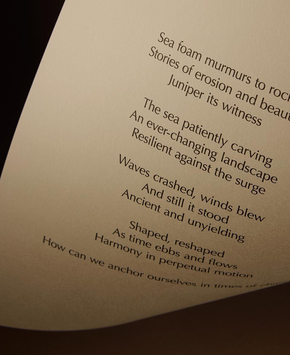 Poem excerpt on cream paper with a folded corner over a deep brown backdrop.