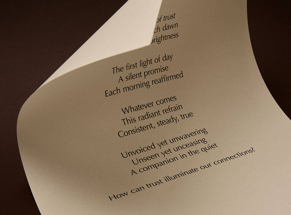 Curved cream page with printed verse against a dark brown background.