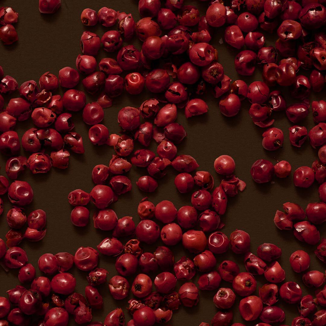 Close-up of red berries scattered across a dark brown surface.